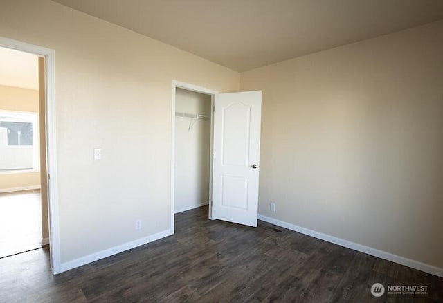 unfurnished bedroom with baseboards, dark wood-style floors, and a closet