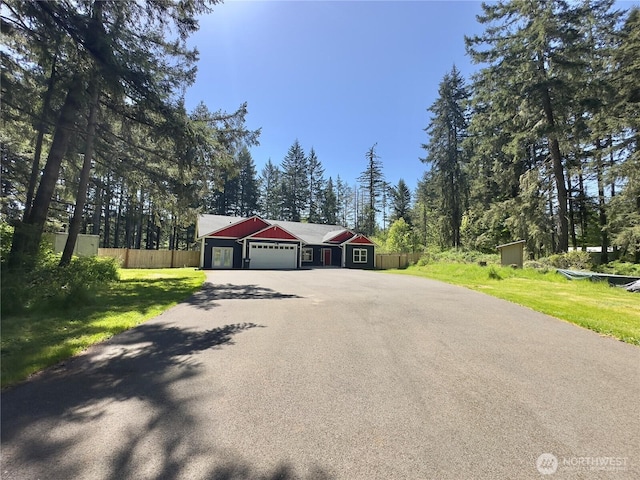 view of front of home with fence, driveway, a front yard, and a garage