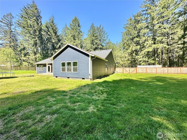 back of property featuring a fenced backyard, a trampoline, a lawn, and crawl space