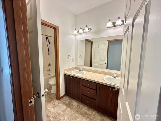 bathroom with double vanity, a sink, shower / bath combination, and toilet