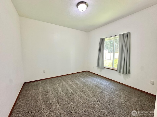 spare room with carpet floors, a textured ceiling, and baseboards
