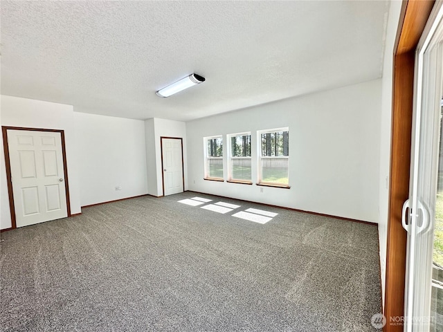 spare room featuring carpet floors, a textured ceiling, and baseboards