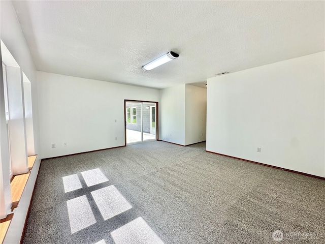 carpeted spare room featuring a textured ceiling, visible vents, and baseboards
