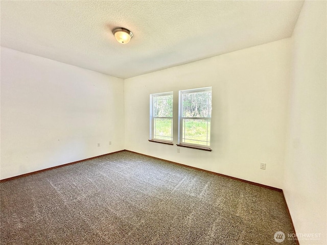 carpeted spare room with a textured ceiling and baseboards