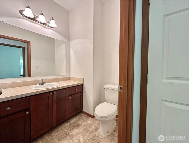 bathroom with toilet, baseboards, and vanity