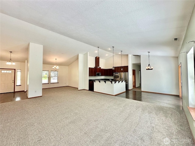 unfurnished living room with an inviting chandelier, dark carpet, and lofted ceiling