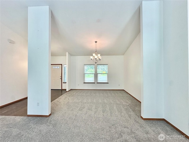 carpeted spare room featuring baseboards, an inviting chandelier, and vaulted ceiling