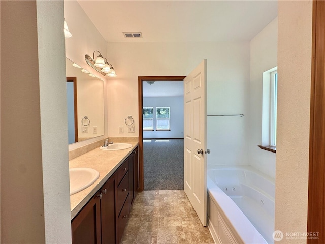 full bath featuring visible vents, a sink, double vanity, and a jetted tub