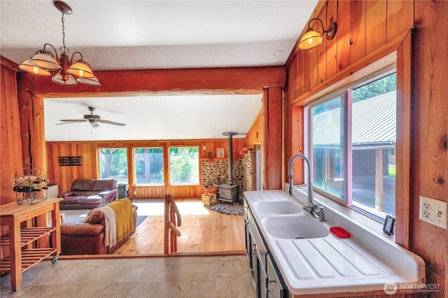 kitchen featuring wood walls, pendant lighting, a sink, and a wood stove