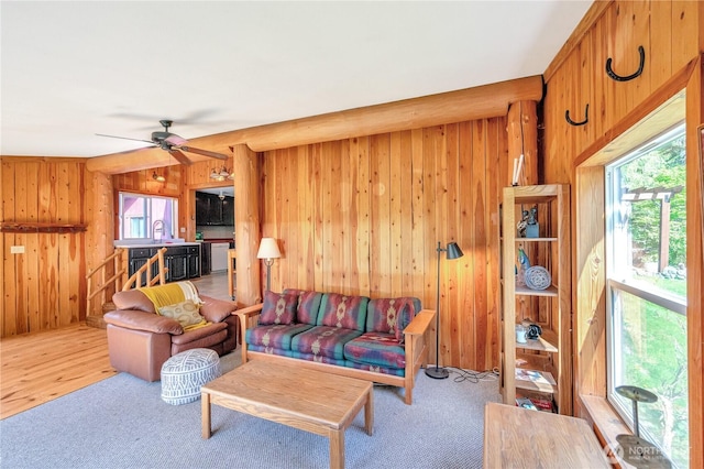 living area with ceiling fan, carpet, and wood walls