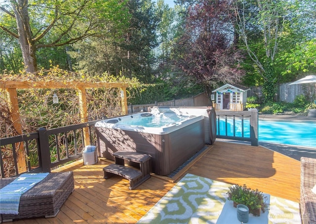 deck featuring a hot tub, an outbuilding, a fenced backyard, and an outdoor pool