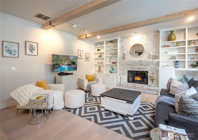 living area with visible vents, a brick fireplace, wood walls, wood finished floors, and beamed ceiling