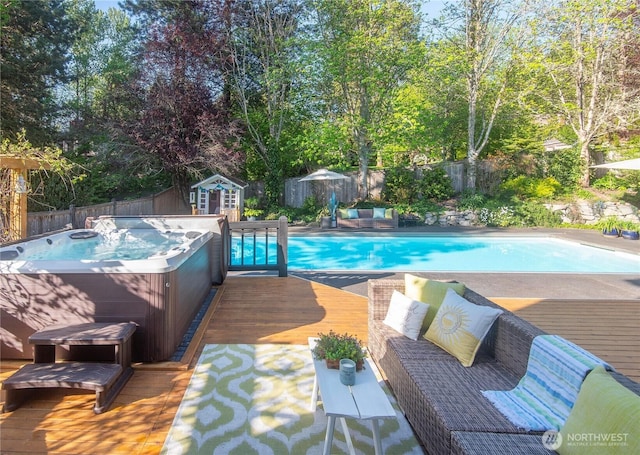view of pool with a wooden deck, a hot tub, a fenced in pool, an outdoor structure, and a fenced backyard