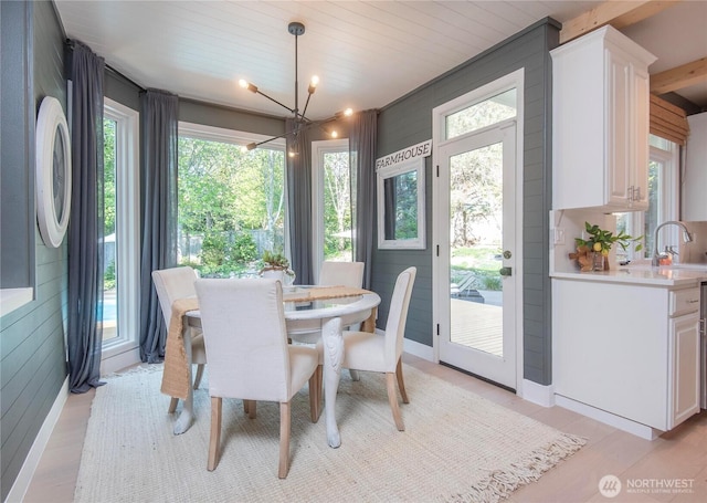 dining area with a chandelier, wood walls, and light wood-type flooring