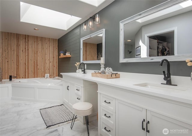 full bath featuring a bath, wood walls, marble finish floor, and a sink