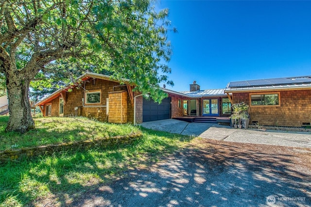 97 Snowberry Ln, Orcas Island, WA 98245 - rear view of property featuring a garage, a chimney, a standing seam roof, concrete driveway, and a metal roof