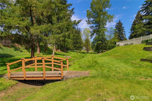 view of property's community with fence, a yard, and a deck
