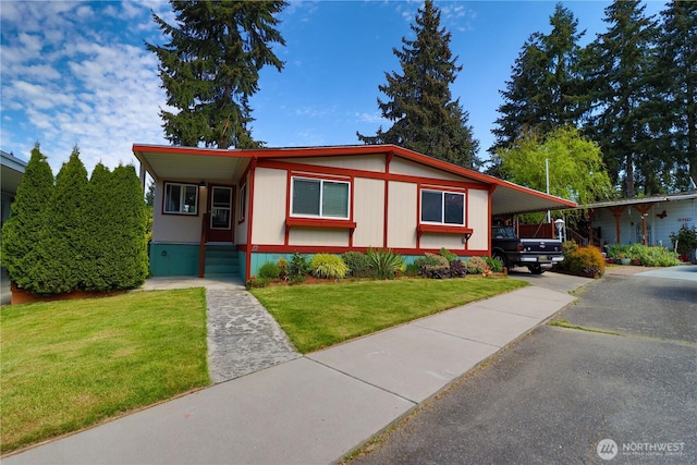 manufactured / mobile home featuring a front lawn, aphalt driveway, and a carport
