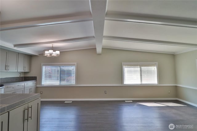 interior space featuring a healthy amount of sunlight, baseboards, gray cabinetry, and dark wood-style floors