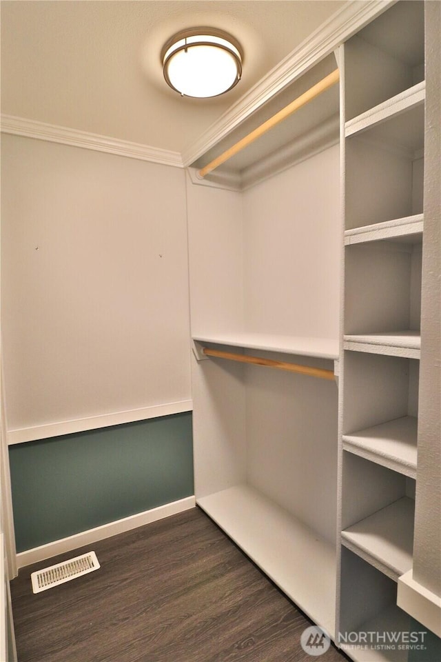 walk in closet with dark wood finished floors and visible vents