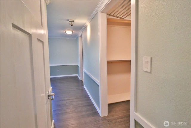 corridor featuring dark wood-style flooring, a textured wall, and ornamental molding