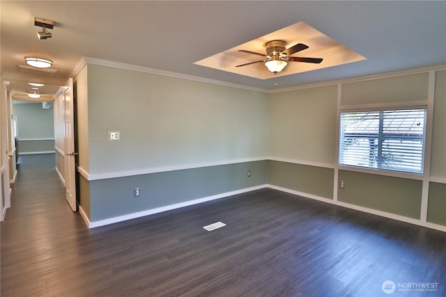 unfurnished room with dark wood-style flooring, a ceiling fan, ornamental molding, and a tray ceiling