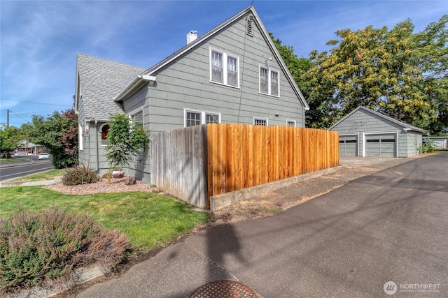 view of property exterior with a garage, a chimney, fence, an outbuilding, and roof with shingles