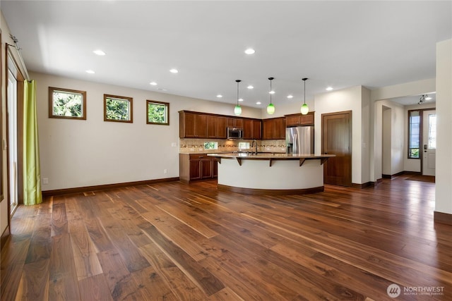 kitchen with a breakfast bar area, backsplash, appliances with stainless steel finishes, a sink, and recessed lighting