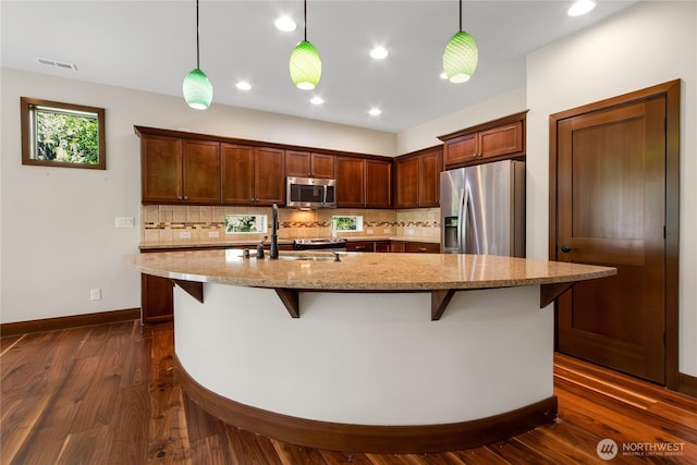 kitchen with a sink, appliances with stainless steel finishes, backsplash, and dark wood-style floors