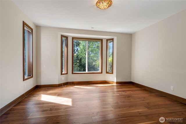 spare room with baseboards, visible vents, and hardwood / wood-style floors