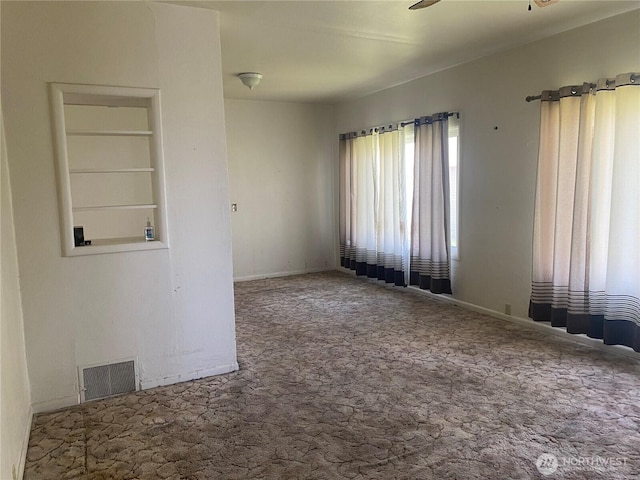 empty room with baseboards, visible vents, ceiling fan, and carpet floors