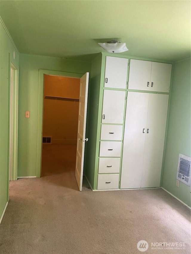 unfurnished bedroom with baseboards, visible vents, carpet, and heating unit