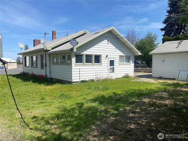 rear view of house featuring a chimney and a lawn