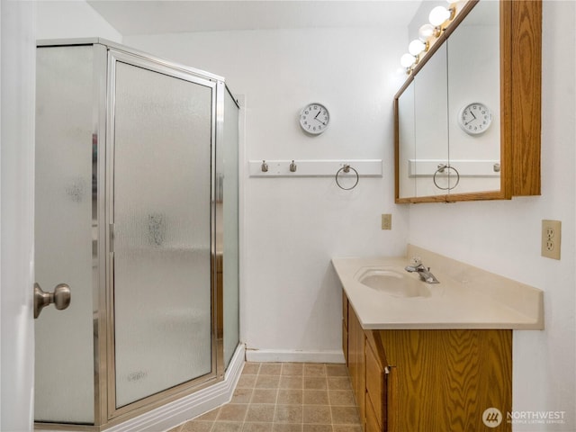 full bathroom with baseboards, a stall shower, and vanity