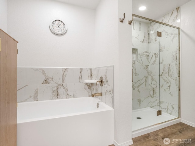 full bath featuring a garden tub, a marble finish shower, and wood finished floors