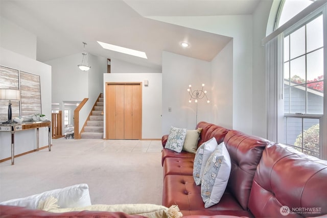 carpeted living area with a skylight, baseboards, stairs, and high vaulted ceiling