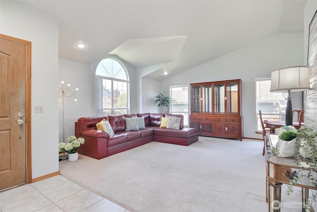living room featuring light tile patterned floors, baseboards, lofted ceiling, and light colored carpet