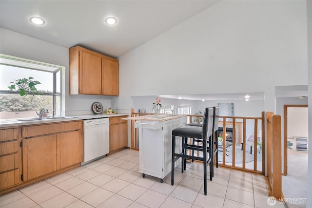 kitchen with white dishwasher, recessed lighting, light countertops, a sink, and vaulted ceiling
