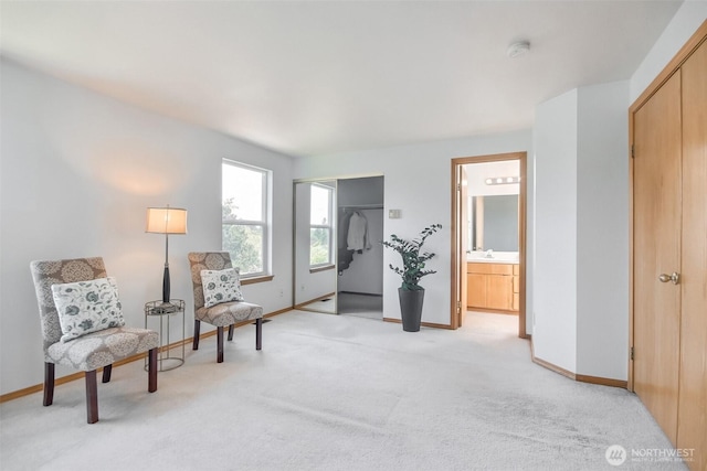 living area featuring baseboards and light colored carpet