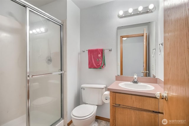bathroom featuring toilet, a shower stall, and vanity