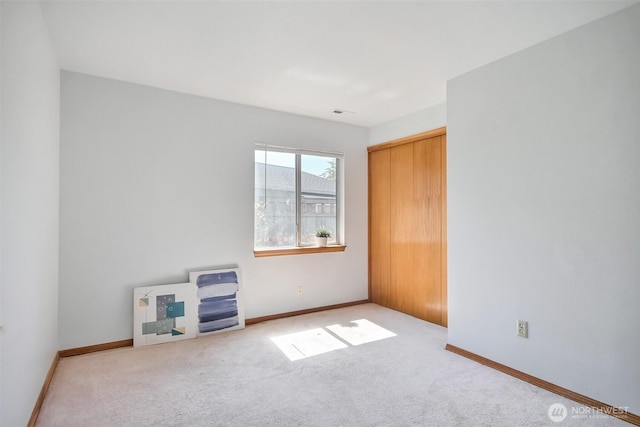 unfurnished room featuring baseboards and light colored carpet