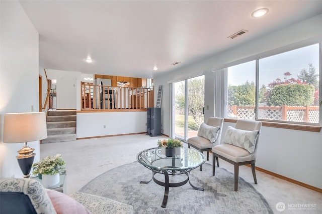 living area with baseboards, carpet, visible vents, and stairway