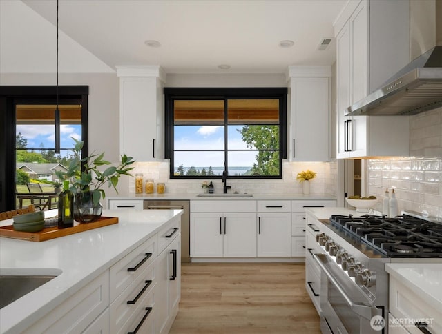 4306 Quaternary Rd, Clinton, WA 98236 - kitchen with decorative backsplash, high end stove, white cabinetry, a sink, and wall chimney exhaust hood