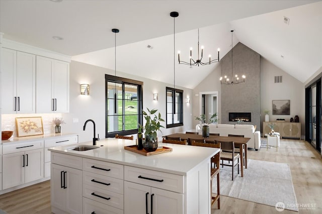 4306 Quaternary Rd, Clinton, WA 98236 - kitchen featuring an inviting chandelier, a sink, high vaulted ceiling, light wood-style flooring, and a center island with sink