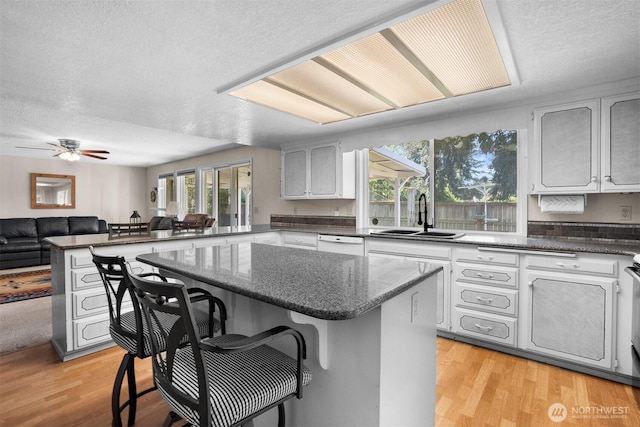 kitchen featuring a sink, a textured ceiling, a peninsula, and a kitchen bar