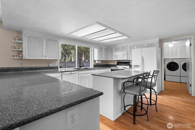 kitchen featuring a sink, white appliances, a textured ceiling, and washer and dryer