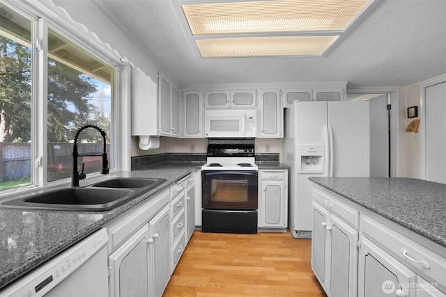 kitchen featuring a sink, light wood finished floors, white appliances, and white cabinetry