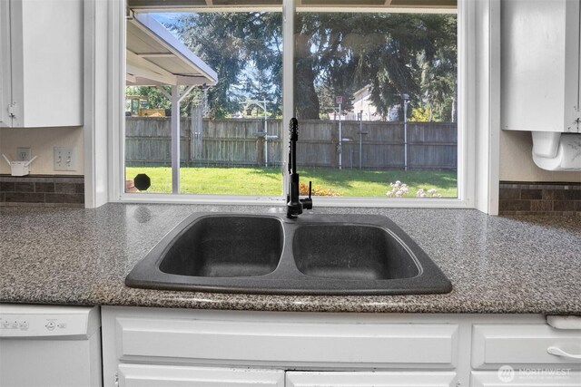 interior details featuring a sink, dishwasher, white cabinets, and tasteful backsplash