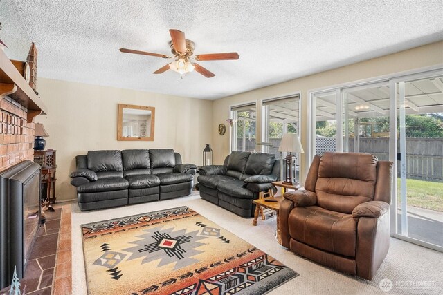 living area with a textured ceiling, a brick fireplace, and ceiling fan