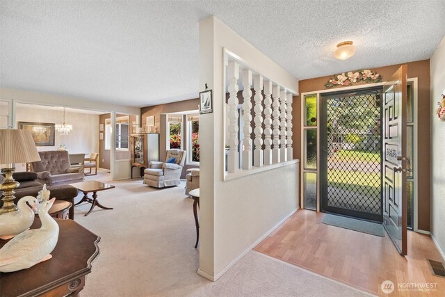 interior space with baseboards, carpet flooring, a textured ceiling, and a notable chandelier